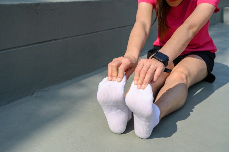 Runner woman trying to do foot stretching for prevent injuries. The benifit of stretching can increasing flexibility performance and reduce risk of injury.